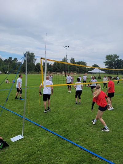 Gruppenspiel auf einem Volleyballfeld, Spieler in Schwarz und Weiß, einige in Rot.