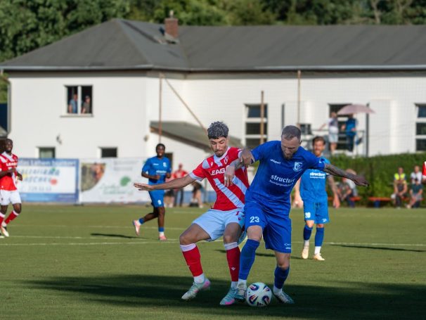 Ein Fußballspieler schirmt den Ball vor dem gegnerischen Spieler ab.