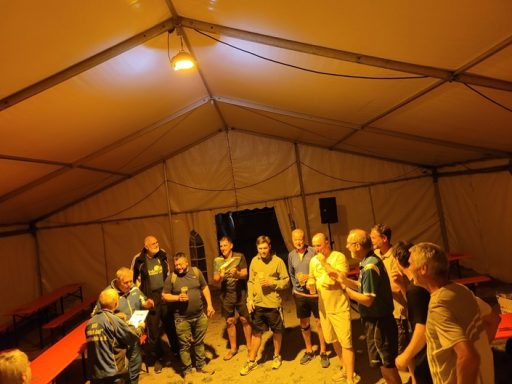 Siegerehrung TT Gruppengespräch in einem großen Zelt mit mehreren Personen und Tischen.