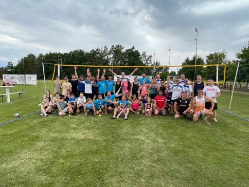 Volleyball-Teams Gruppenfoto von vielen Menschen am Sportplatz, lächelnd und in Sportkleidung.