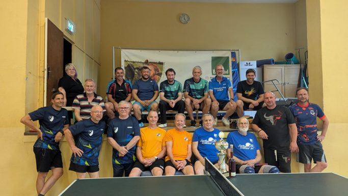 Alle Aktiven Eine Gruppe von 16 Tischtennisspielern mit Pokal in einer Sporthalle.